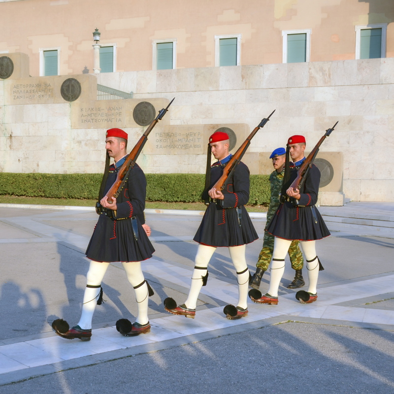 11 - Evzones, members of the Greek Presidential Guard, performing a ceremonial march wearing their distinctive service uniforms in front of the Tomb of the Unknown Soldier at Syntagma Square